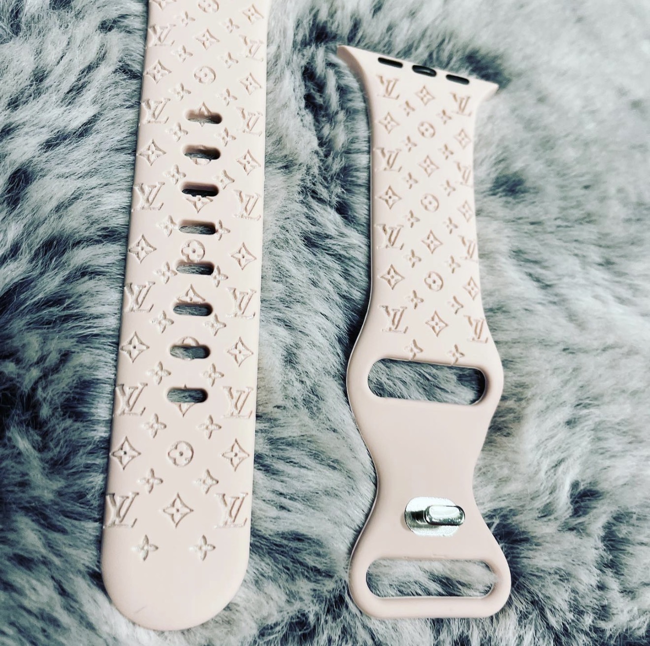 Pink Apple Watch band laser-engraved with a repeating designer monogram pattern.